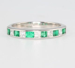 An 18ct white gold princess cut diamond and baguette cut emerald half eternity ring size N  