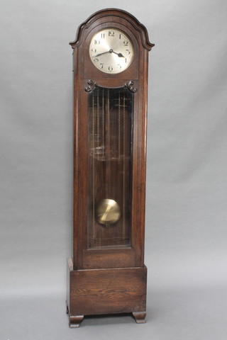 A 1930's 8 day chiming longcase clock with 10" silvered dial and Arabic numerals contained in an oak arched case, raised on bracket feet 74"h 