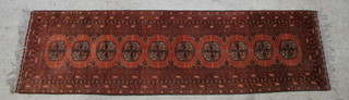 A red ground Afghan runner with 10 octagons to the centre within a multi-row border 118 1/2" x 32 1/2" 