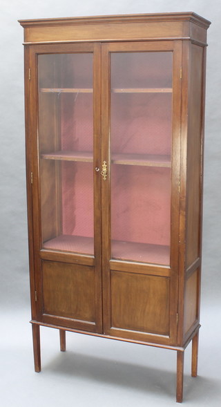 An Edwardian mahogany display cabinet with moulded cornice, fitted shelves enclosed by glazed panelled doors and raised on square tapering supports 72"h x 34"w x 13"d 
