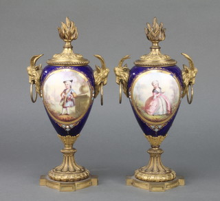 A pair of 19th Century Sevres style tapered vases, the blue ground with panels of figures and musical instruments, having gilt metal mounts and rams head handles with reversible flambe/candle holder covers and quatrefoil bases 9"  