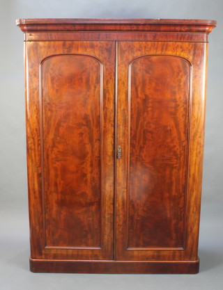 A Victorian mahogany D shaped wardrobe with moulded cornice the interior with hanging space and 3 drawers enclosed by arched panelled doors, raised on on a platform base 82"h x 61"w x 24"d 