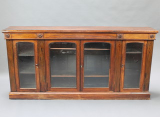 An early Victorian rosewood side cabinet fitted triple cupboards enclosed by arched panelled doors, raised on a platform base 35 1/2"h x 72"w x 12"d 