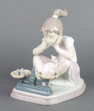A Lladro group of a girl weighing a cat in a set of scales 5474 6 1/2" 