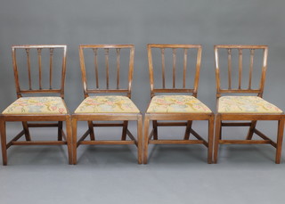 A set of 4 19th Century mahogany stick and rail back dining chairs with upholstered Berlin woolwork drop in seats, raised on turned square tapering supports with H framed strecher 