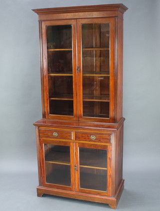A Victorian mahogany bookcase on cabinet with moulded cornice, the upper section fitted adjustable shelves enclosed by glazed panelled doors, the base fitted fitted 2 short drawers and a cupboard enclosed by glazed panelled doors, raised on bracket feet 82"h x 36"w x 19"d 