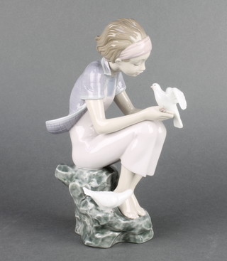 A Lladro figure of a girl sitting on a rock with a dove, a 2011 annual piece, 8" 