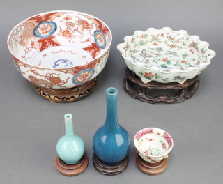 A 19th Century Chinese celadon shaped shallow dish decorated with insects and flowers on a raised on a hardwood stand 9", a Chinese blue glazed bottle vase 7", a turquoise ditto 3 1/2",  a tea bowl with moulded floral decoration and a late 19th Century Imari deep bowl decorated with panels of Shi Shi and pavilions 