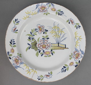 An 18th Century English Delft polychrome plate decorated with a garden view enclosed within a border of flowers 13" 