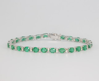 An 18ct white gold emerald and diamond line bracelet, the emeralds 9.07ct, diamonds 0.63ct