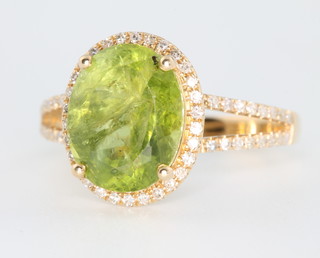 A 14ct yellow gold oval peridot and diamond dress ring with open shank, the centre stone approx. 4.41ct surrounded by brilliant cut diamonds approx 0.4ct, size M 1/2 