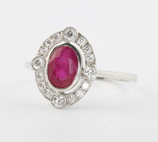 An 18ct white gold oval ruby and diamond cluster ring, the ruby approx 1.19ct surrounded by brilliant cut diamonds approx. 0.35ct, size O 1/2