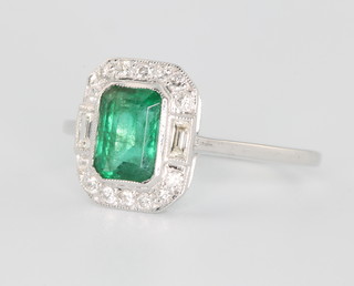 An 18ct white gold emerald and diamond ring the centre stone approx 0.6ct surrounded by brilliant and baguette diamonds size N 