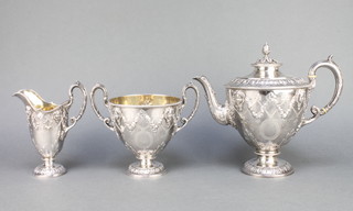 A good mid Victorian repousse silver three piece tea set comprising tea pot, milk jug and sugar bowl decorated with masks, acanthus leaves, ribbons and floral garlands. London 1865. Makers  Edward & John Barnard. Gross 1602 grams.