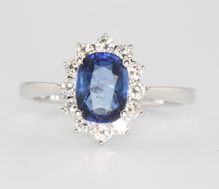 An 18ct white gold oval sapphire and diamond cluster ring, the sapphire approx. 2.15ct surrounded by 12 brilliant cut diamonds, size O