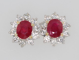 A pair of 18ct white gold oval ruby and diamond ear studs, the rubies approx. 3.02ct each surrounded by 10 brilliant diamonds approx. 1.36ct 