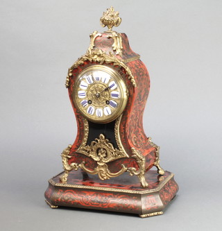 A 19th/20th Century French 8 day striking clock with gilt and porcelain dial contained in a shaped red boulle case surmounted by an urn, the back plate marked Z CIE Paris 6402 13"h x 7"w x 4"d raised on a rectangular base 