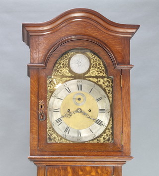 An early 20th Century 8 day longcase clock striking on a gong, the 12" arched gilt dial with silvered chapter ring and calendar aperture, complete with pendulum and weights, contained in an oak case 87"h 