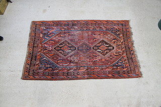 A rust blue and red ground Persian Qashqai rug with 3 stylised diamonds to the centre within a multi row border 90" x 58" 