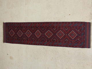 A red and blue ground Meshwani runner with 7 stylised diamonds to the centre within a multi row border 102" x 25 1/2" 