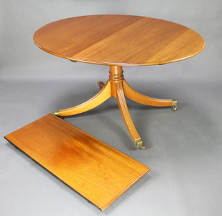 A Georgian style oval mahogany pedestal extending dining table raised on gun barrel and tripod supports, brass caps and castors 28 1/2"h x 42"w x 54" extending to 72" 