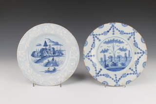 An 18th Century Delft blue and white plate decorated with a fisherman, figures in a boat before buildings with a white floral border 9", a ditto decorated with a garden landscape enclosed within floral swags 9" 