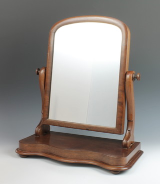 A Victorian arched plate dressing table mirror contained in a mahogany swing frame, the base of serpentine outline 21"h x 19"w x 8"