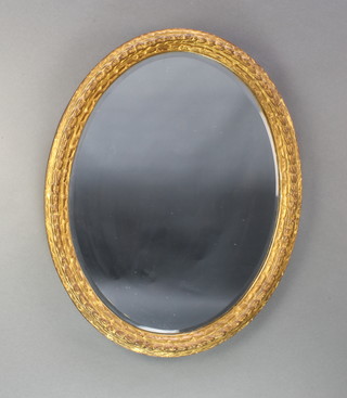 A 19th Century oval bevelled plate wall mirror contained in a decorative gilt frame 29" x 23"