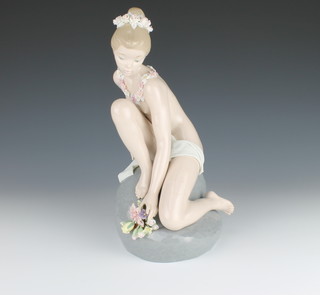 A Lladro figure of a semi-clad girl sitting on a rock holding flowers 1601 12" 