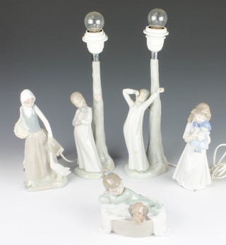 A pair of Nao table lamps in the form of children standing beside tree trunks 11", do. figure of a lady with goose 10", a girl with doll 8" and a girl with puppy 5 1/2" 