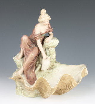 A Royal Dux figure of a water carrier sitting beside a rocky outcrop on a shell bowl 9" 