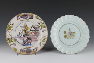 An 18th Century Bristol Delft polychrome dish decorated a boat before a building enclosed in a floral border 9 1/4", an English do. decorated with a figure before a pavilion in a garden with white floral rim 9" 