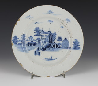 An 18th Century English Delft blue and white plate decorated with a figure in a boat, castle and buildings 9" 