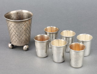 Six Continental silver tots with chased motifs and a do. cup on ball feet, 170 grams