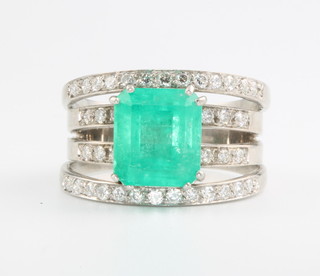An 18ct white gold emerald and diamond open ring the baguette cut centre stone approx. 5.6ct supported on 4 bands of brilliant cut diamonds size U 