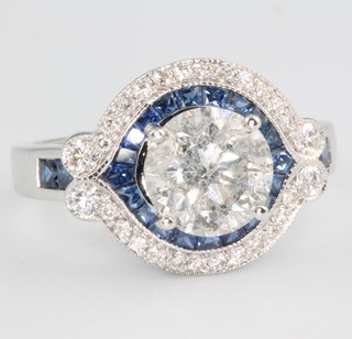 An 18ct white gold diamond and sapphire ring, the brilliant cut diamond approx. 2.11ct surrounded by princess cut sapphires approx. 1.14ct and brilliant cut diamonds approx. 0.34ct, size N