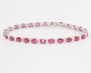 An 18ct white gold ruby and diamond tennis bracelet, the oval cut rubies approx. 12.60ct (26) and brilliant cut diamonds approx. 0.63ct, 170mm long 