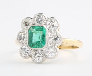 An 18ct yellow gold emerald and diamond cluster, the emerald approx. 0.6ct, the 8 brilliant cut diamonds approx. 0.8ct, size O