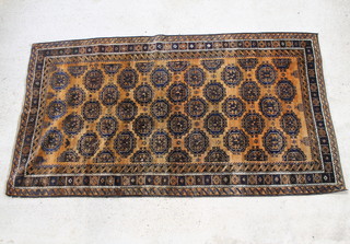 A rust and black ground Afghan rug with stylised octagons to the centre within a multi row border 108" x 60" 