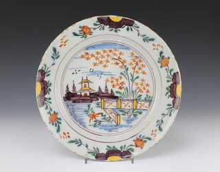 An 18th Century English Delft polychrome dish decorated with a pavilion and birds in a garden landscape within stylised flowers 12"