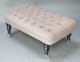 A rectangular Victorian style stool upholstered in grey buttoned material, raised on turned ebonised supports silvered casters 18"h x 45"w x 27"d