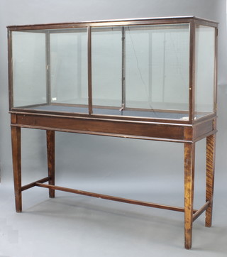 A museum quality rectangular mahogany and glass display cabinet raised on square tapered supports with H framed stretcher 70 1/2"h x 73"w x 25"d 
