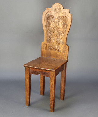 A George V carved oak hall chair the solid back dated 1911, carved monogram with solid seat, raised on turned and fluted supports