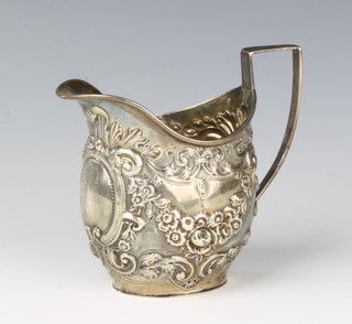 A Victorian repousse silver cream jug decorated flowers and scrolls, London 1893, 109gms