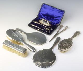 An Edwardian silver mounted 4 piece manicure set comprising scissors, 2 brushes and a pair of glove stretchers, cased