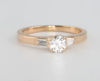 An 18ct yellow gold single stone diamond ring, approx 0.4ct flanked by tapered baguette cut diamonds, size K 1/2