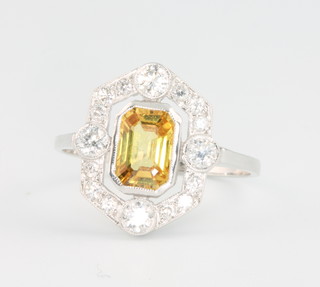 An 18ct white gold yellow sapphire and diamond Art Deco style ring, the emerald cut centre stone approx 1.0ct surrounded by brilliant cut diamonds, size O 1/2