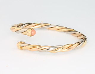 Cartier, an 18ct two colour gold rope twist bangle with cabochon coral terminals No 00067 1990