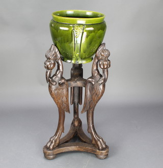An Art Nouveau green glazed jardiniere raised on a carved hardwood stand 