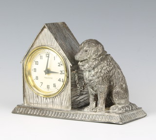 A 1930's bedroom timepiece with paper dial and Arabic numerals contained in an antimony case decorated a kennel with chained dog 4"h